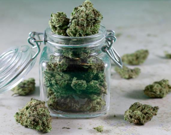 Close-up of cannabis buds stored in a glass jar, symbolizing herbal medicine and lifestyle.